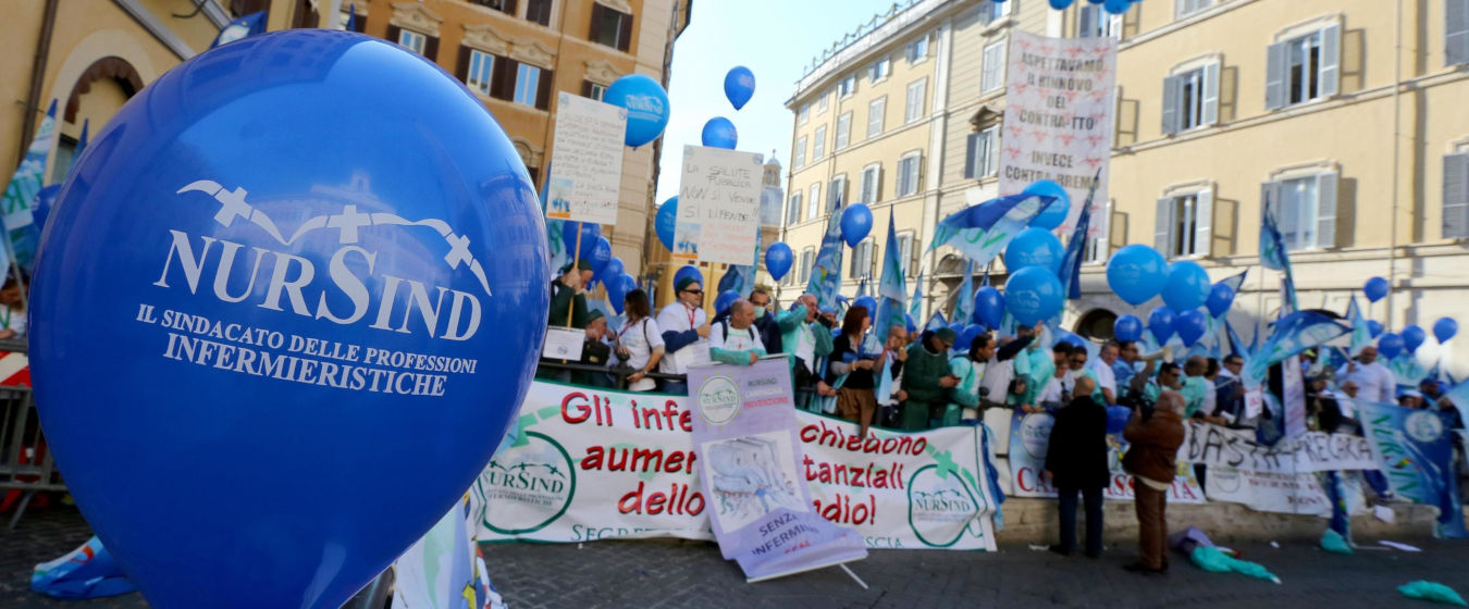 Nursind Teramo manifestazione a Roma per i diritti degli infermieri con persone con mani alzate e palloncini blu